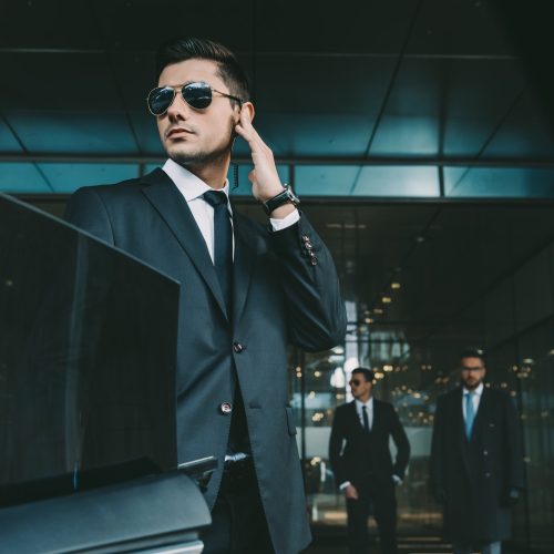 bodyguard-opening-car-door-for-businessman-and-listening-security-earpiece.jpg
